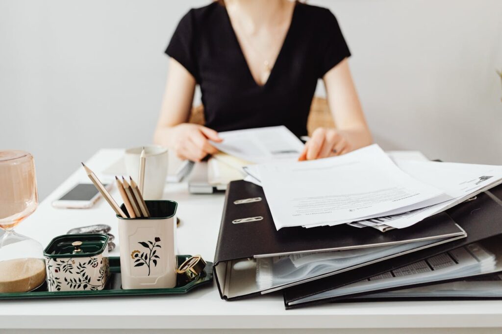 A woman at a desk working with binders and documents, featuring essential office supplies.